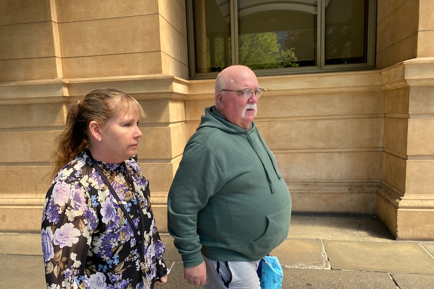 A bald man wearing a green hoodie walking outside of the Adelaide Supreme Court. 