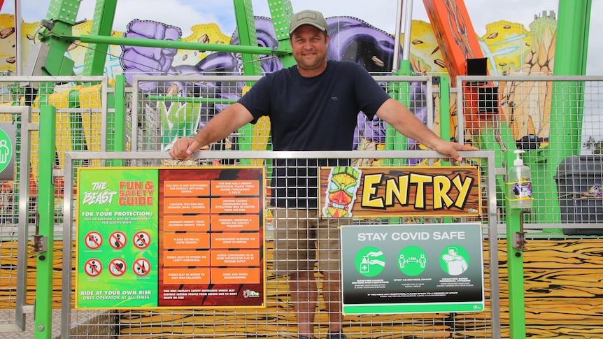 Jamie Pickett leaning on the warning signs on the stairs that enter into his big amusement ride