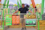 Jamie Pickett leaning on the warning signs on the stairs that enter into his big amusement ride
