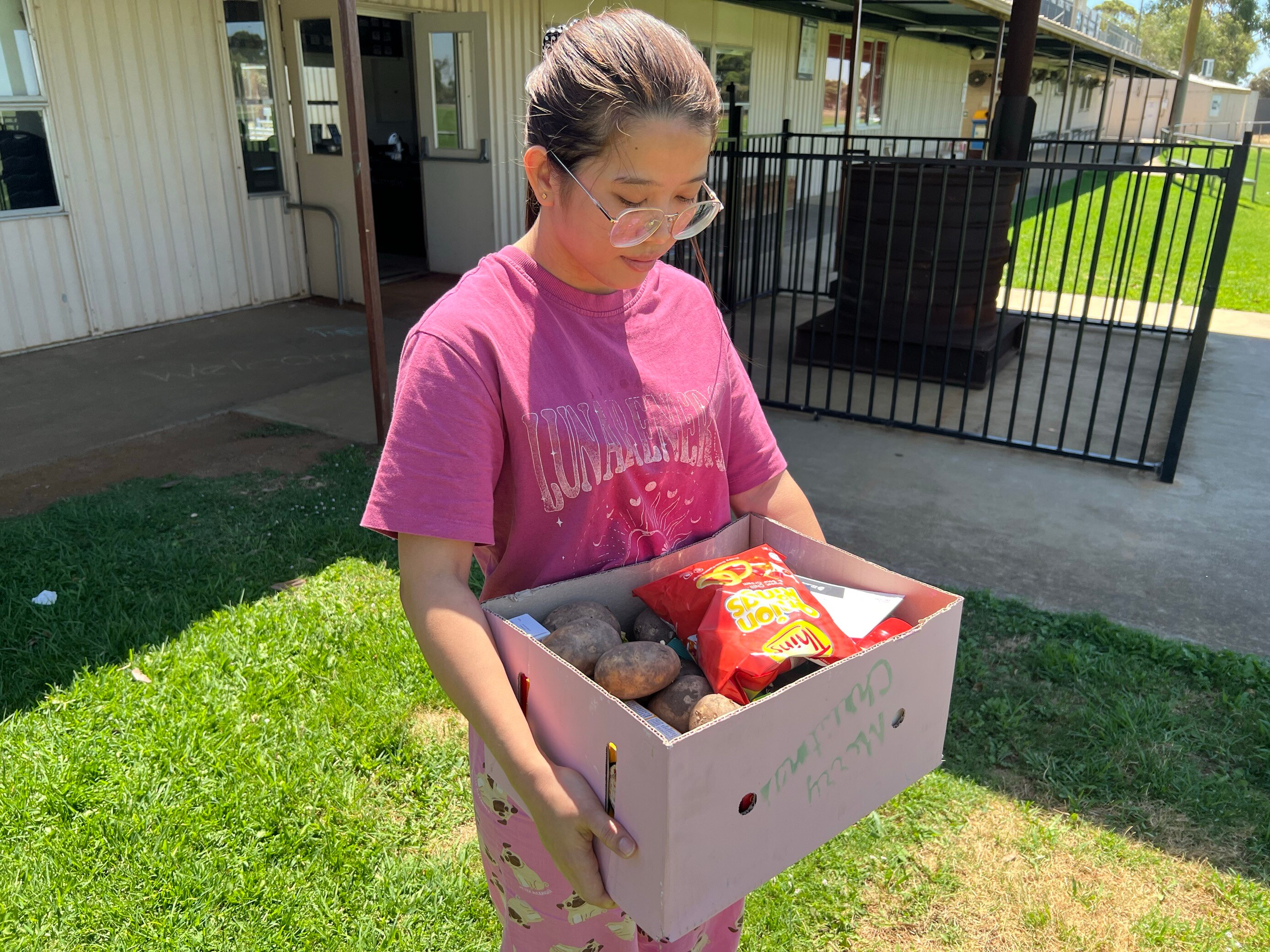 Young woman holds a cardboard box full of food.