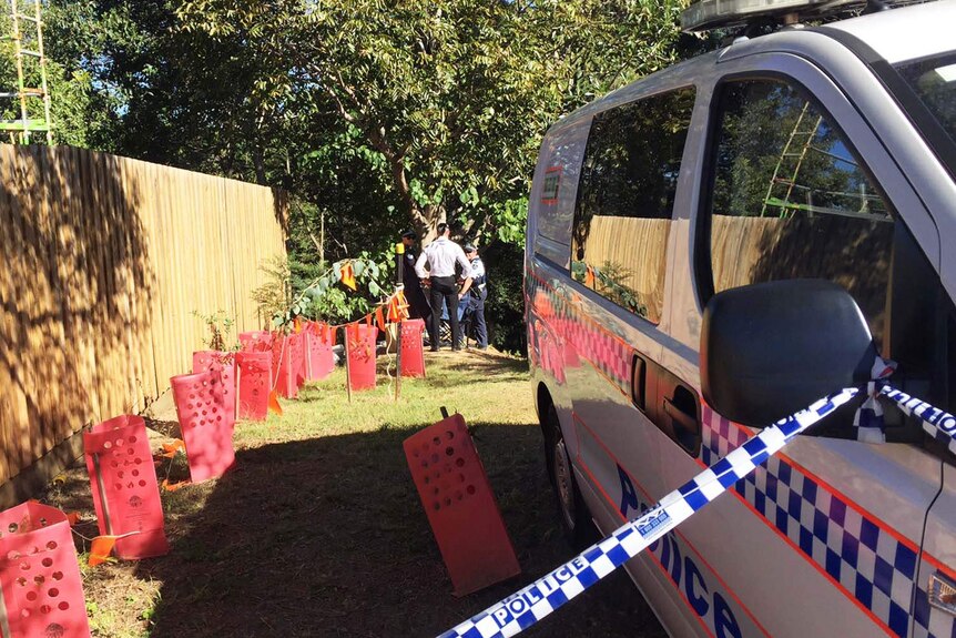 Police tape connected to a police van cordons off a block of land in Teneriffe
