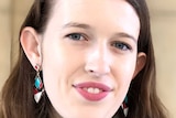 Amelia Morris, a young woman with brown hair, a grey top and colourful earrings.