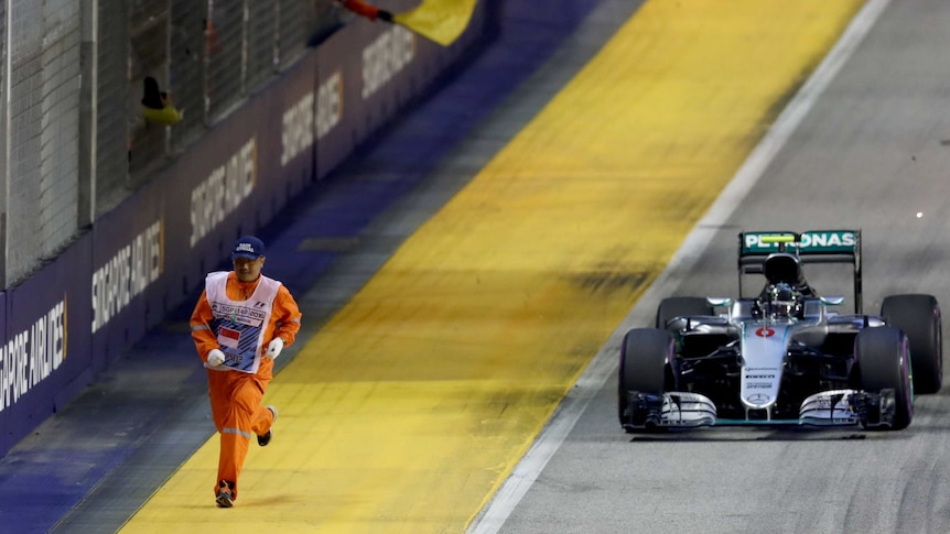F1 marshal runs alongside Nico Rosberg's Mercedes in Singapore