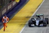 F1 marshal runs alongside Nico Rosberg's Mercedes in Singapore
