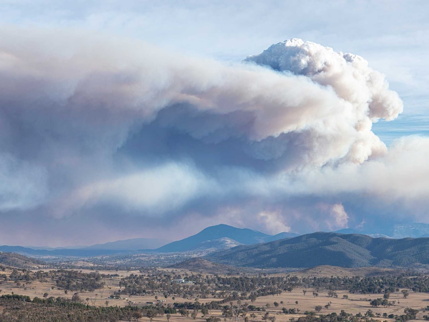 Panorama of hills with smoke from a bushfire behind.