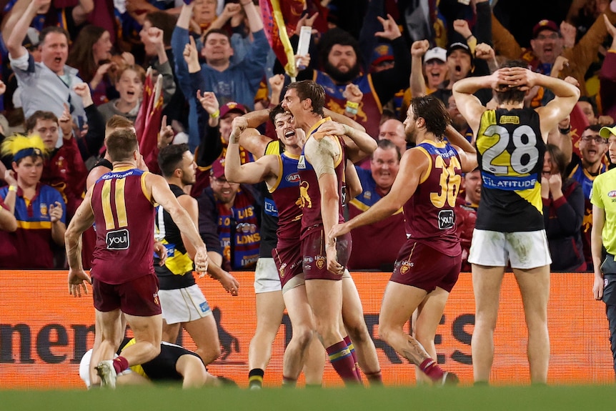 Lions players surround Joe Daniher as the crowd goes wild