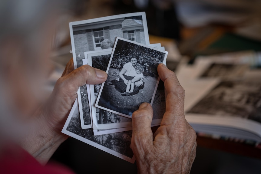 Old woman's hands holding old photos, close-up.