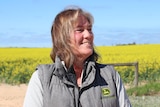 A woman stands in front of a canola crop