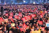 Hundreds of people holding candles and banners reading Park Guen-Hye's arrest
