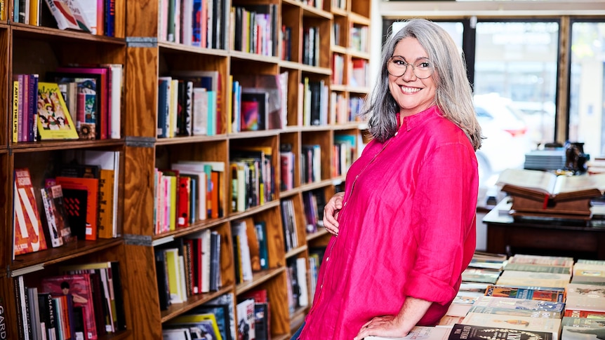 Amber Cunningham in a library or bookstore, with shelves of books everywhere.