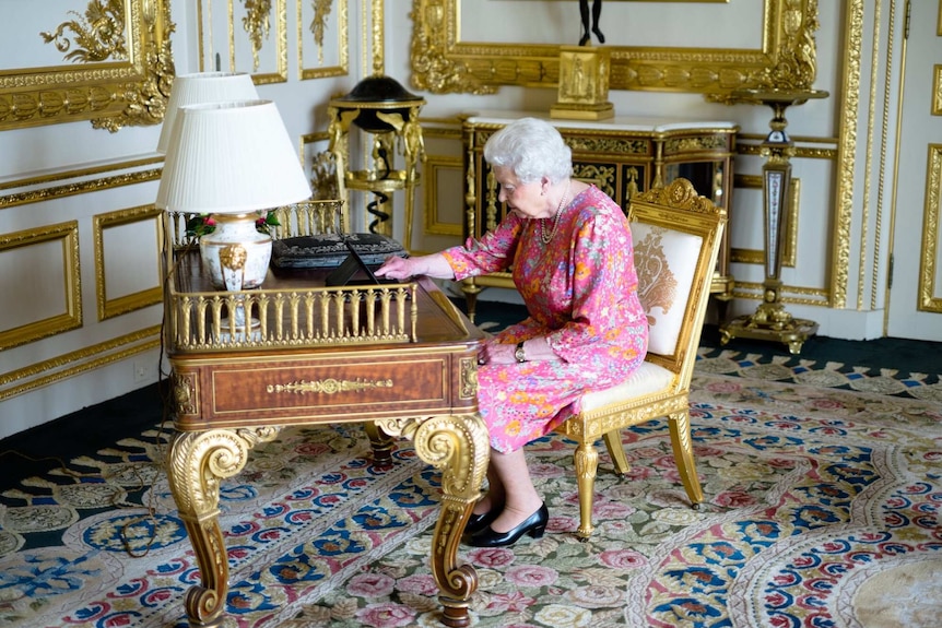 The Queen uses an iPad while sitting at an ornate desk