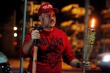 A supporter of US President Donald Trump holds a tiki torch and a pitchfork during a protest.