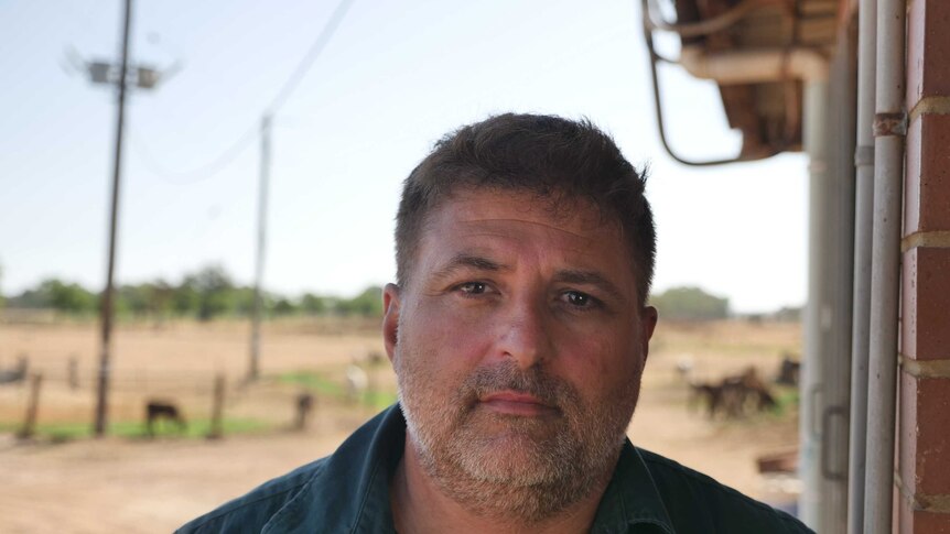 Wokalup farmer Michael Angi is standing at his dairy with cows in the background