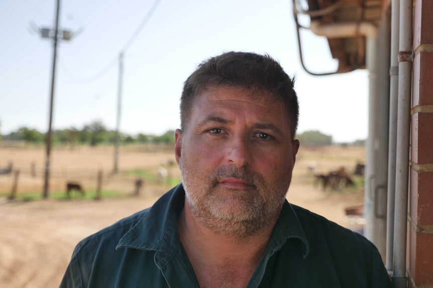 Wokalup farmer Michael Angi is standing at his dairy with cows in the background