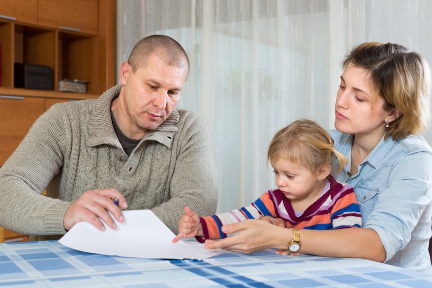 Man and woman looking at paperwork with child