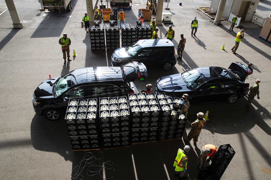 Three cars between lots of crates of milk