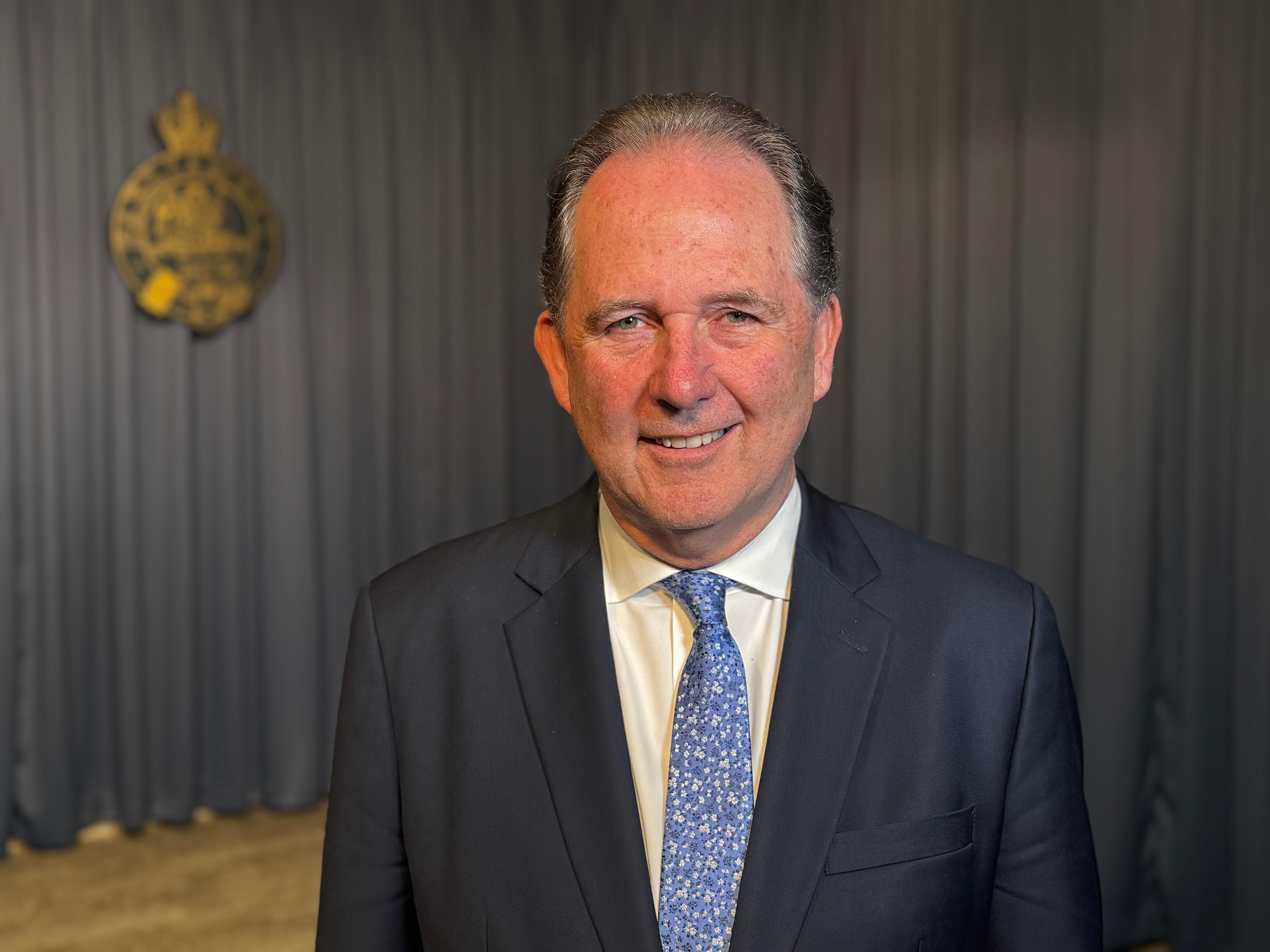 Alister Henskens in suit smiling