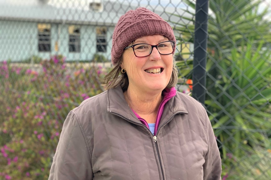 A woman wearing a mauve beanie smiles at the camera.