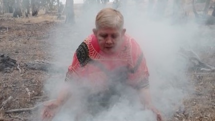 A woman conducts an Aboriginal smoking ceremony