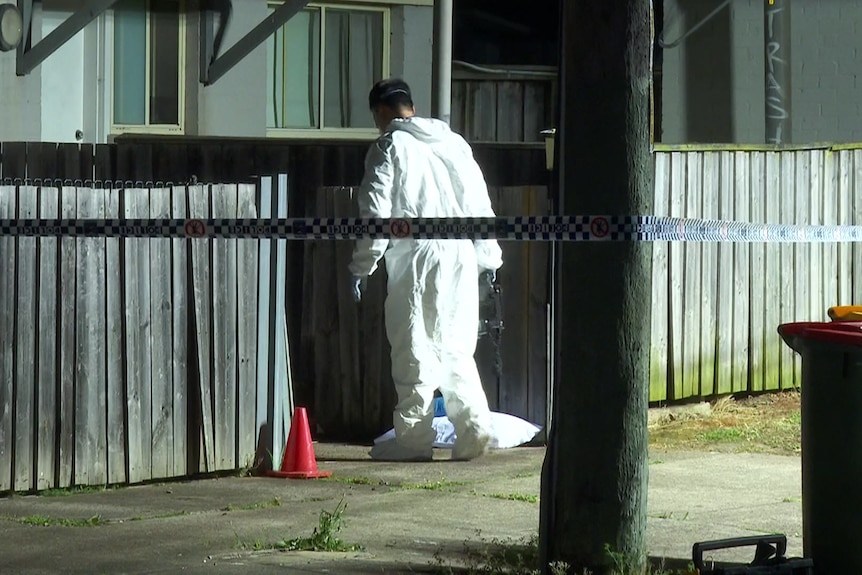 A forensics worker in a white suit at a crime scene at a house