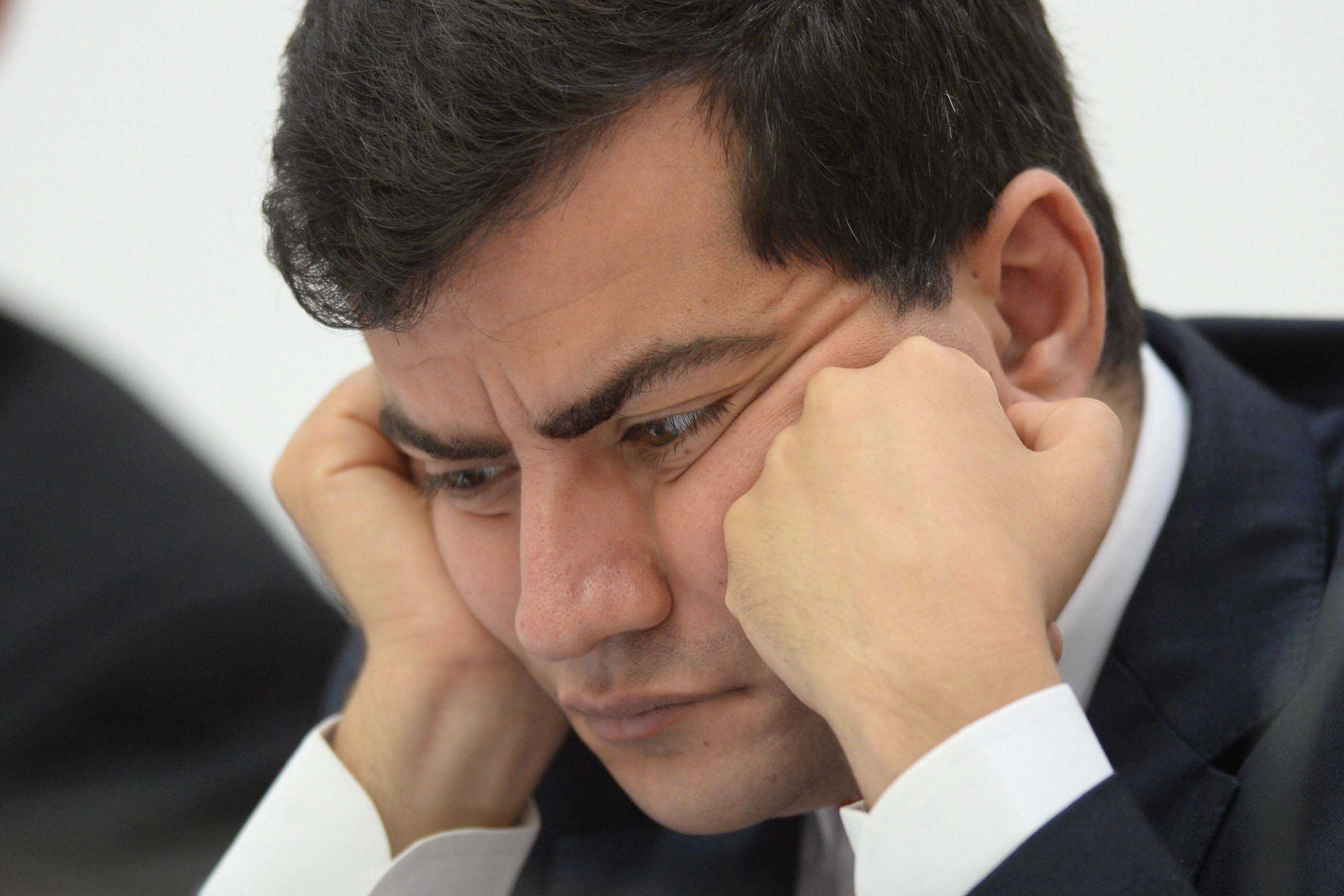 Labor Senator Sam Dastari sits with his face resting on his hands during Senate Hearings, looking concerned and deep in thought.