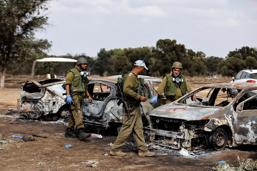 Men in camo gear and gloves near burned cars