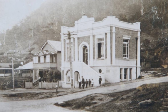 Black and white photo of Clifton School of Arts with a small group of people standing in front of the building.