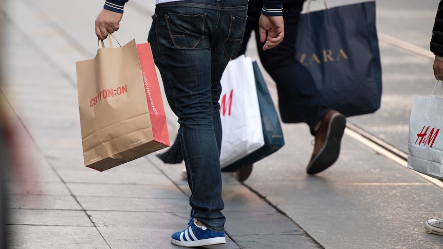 Person holding shopping bags, legs only