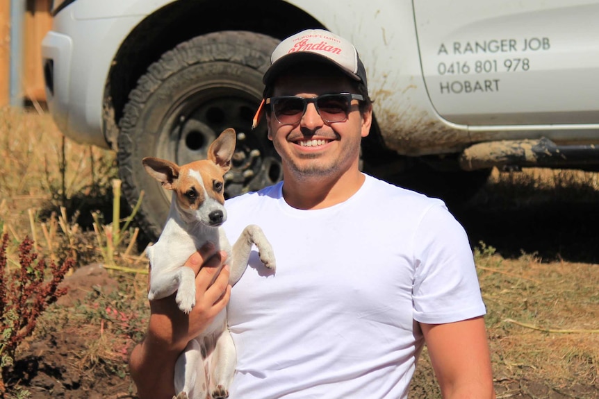 A man holding a jack russell terrier puppy