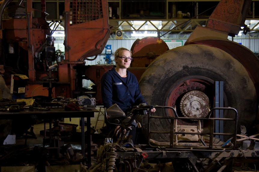 Louise Azzopardi surrounded by workshop tools and a bobcat