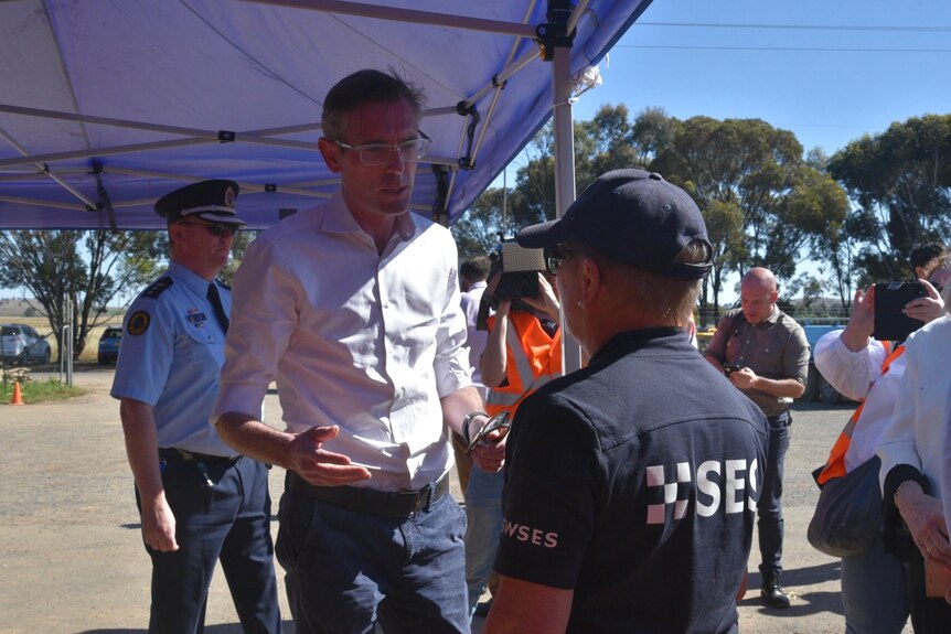 Two men talking with a group of people around them 