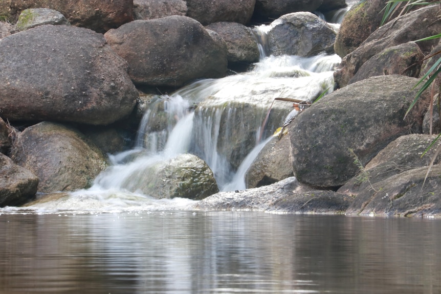 A close-up of a waterfall pouring over granite rocks.