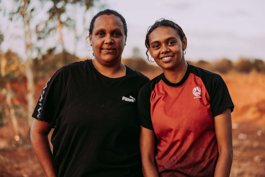 A mother and daughter smiling together.