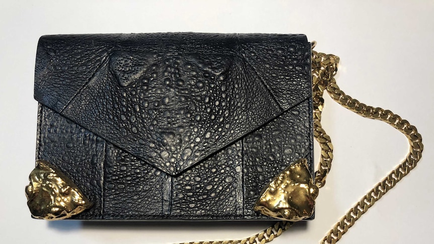 A photo of a black and gold-plated handbag made out of cane toad leather.