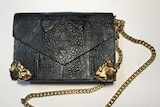 A photo of a black and gold-plated handbag made out of cane toad leather.