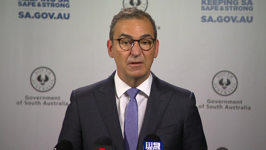 A man wearing a suit and tie in front of a banner