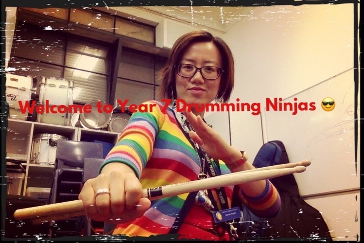 A woman holds a drum stick like a weapon with the words "Welcome to Year 7 Drumming Ninjas"