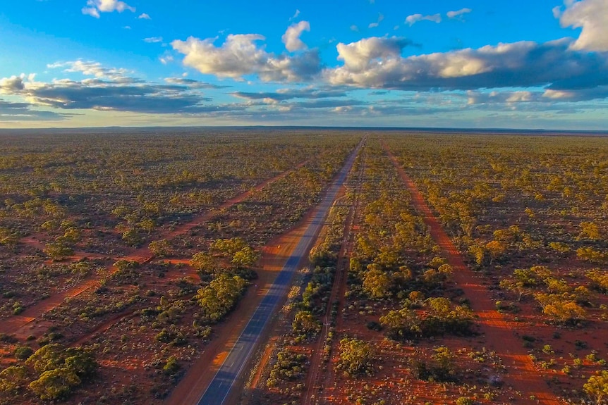 An aerial shot of a remote area, with a lone road running through scrubland.