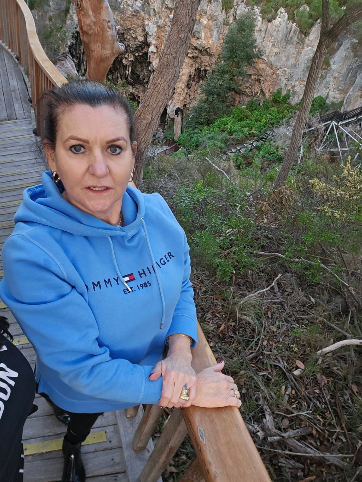 A middle-age woman with dark hair wears a bright blue hoodie. 
