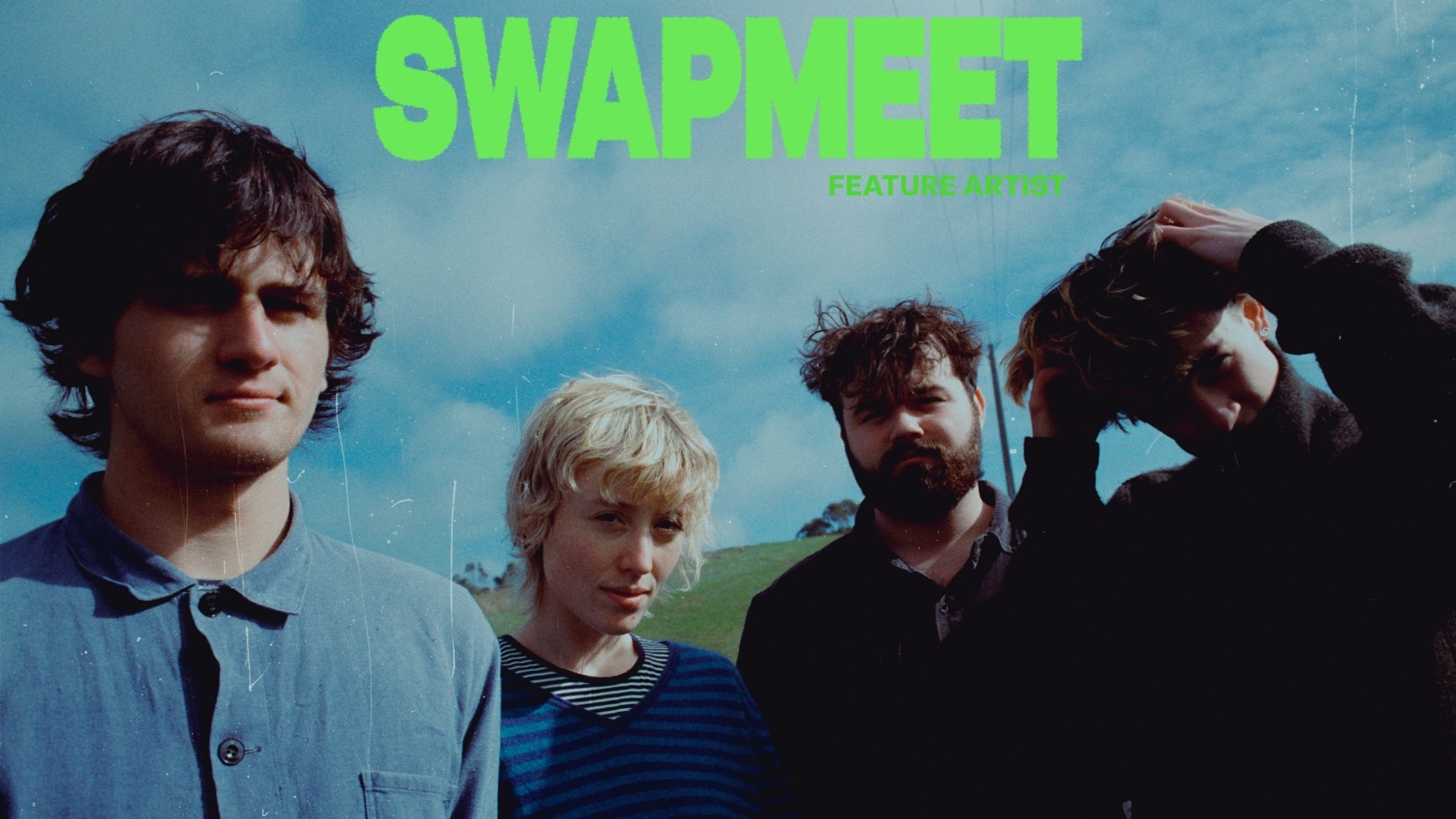 4 people standing looking at the camera against a blue sky