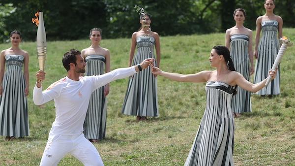 A woman holding a flame torch hands it to a man