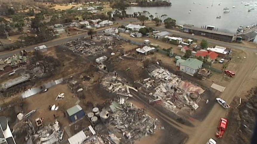 A helicopter flies over fire damage in the coastal town of Dunalley