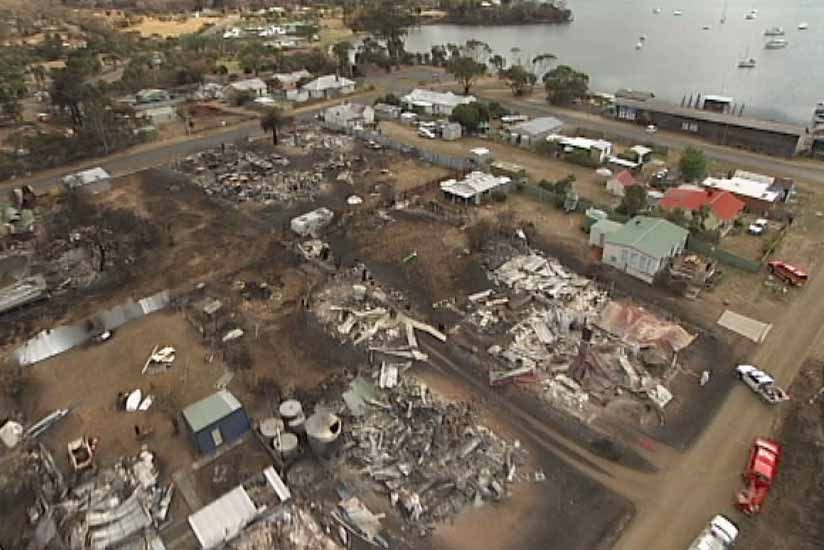 A helicopter flies over fire damage in the coastal town of Dunalley