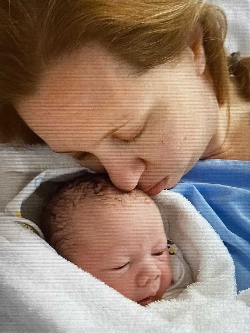 A woman kisses a baby on the head.