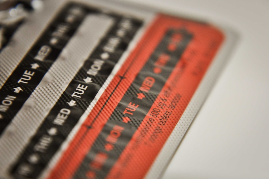 A close up shot of a silver, black and red tab of contraceptive pills.