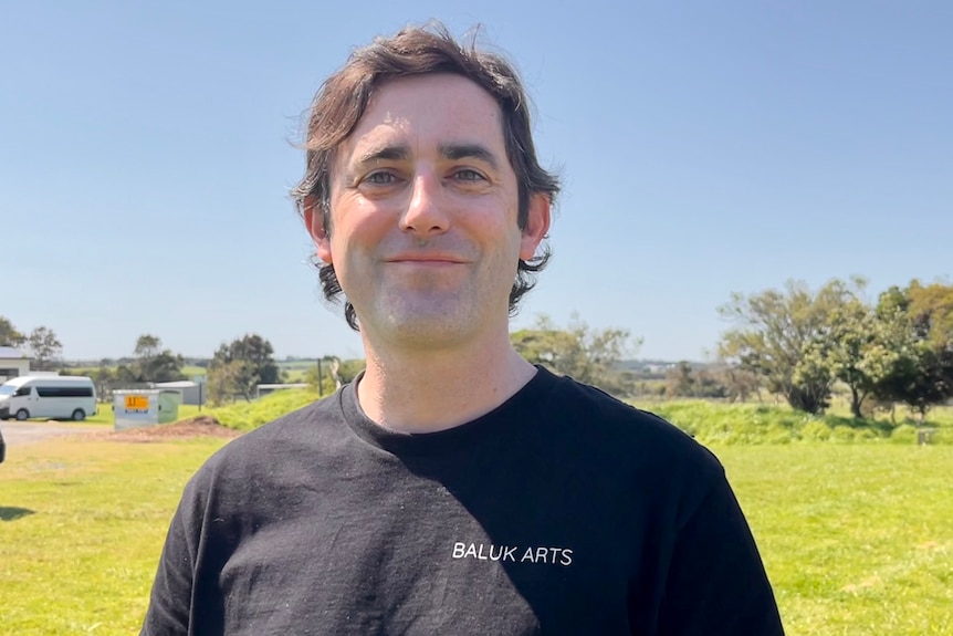 a man standing in a field smiling.