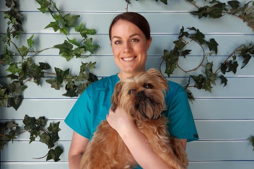 Woman in scrubs holding a dog