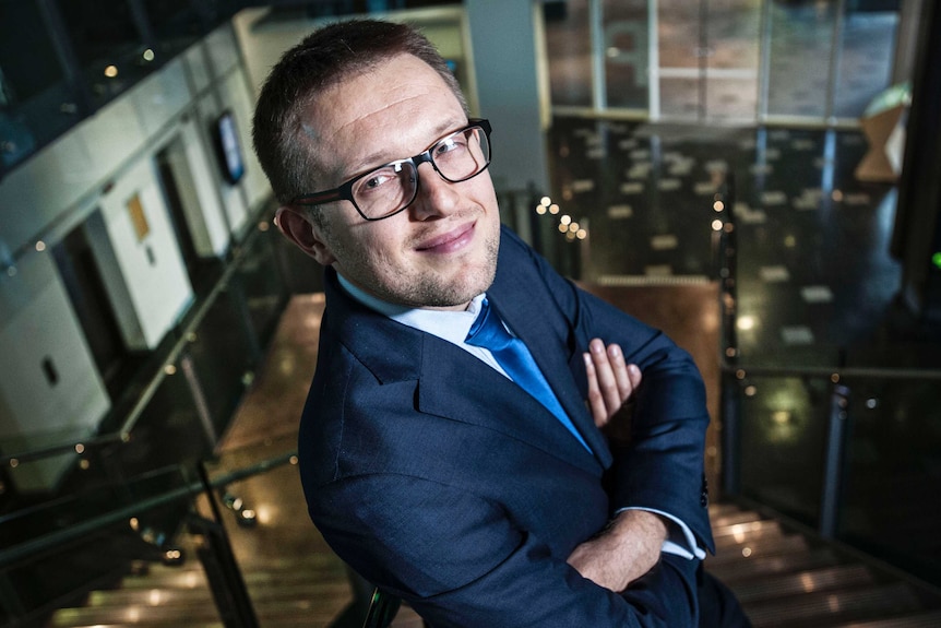 Professor Marek Kowalkiewicz standing on a staircase looking up at the camera