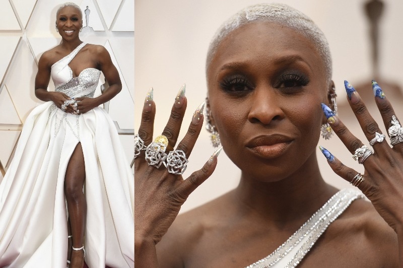 Cynthia Erivo wearing a one should white gown with a high slit, showing off her long, pointed fingernails.