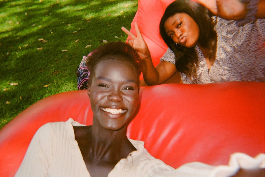 A young African-Australian woman sitting on a red bean bag with her friend